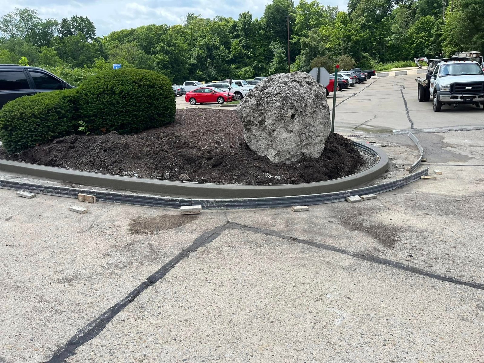 Completed commercial concrete curb and landscape island with boulder in a parking lot