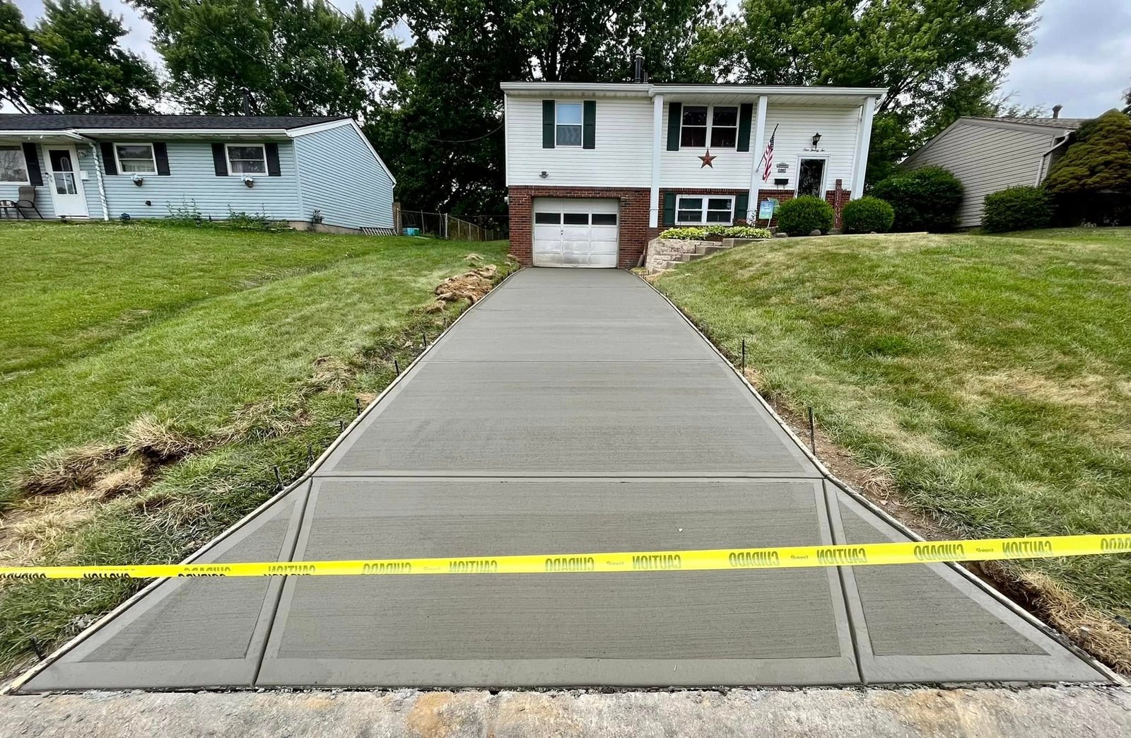 Finished broom-finish concrete driveway replacement at a split-level home