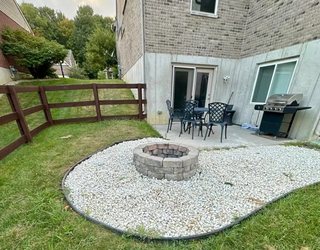 Concrete patio with stone firepit on white rock surround at rear yard of residential home