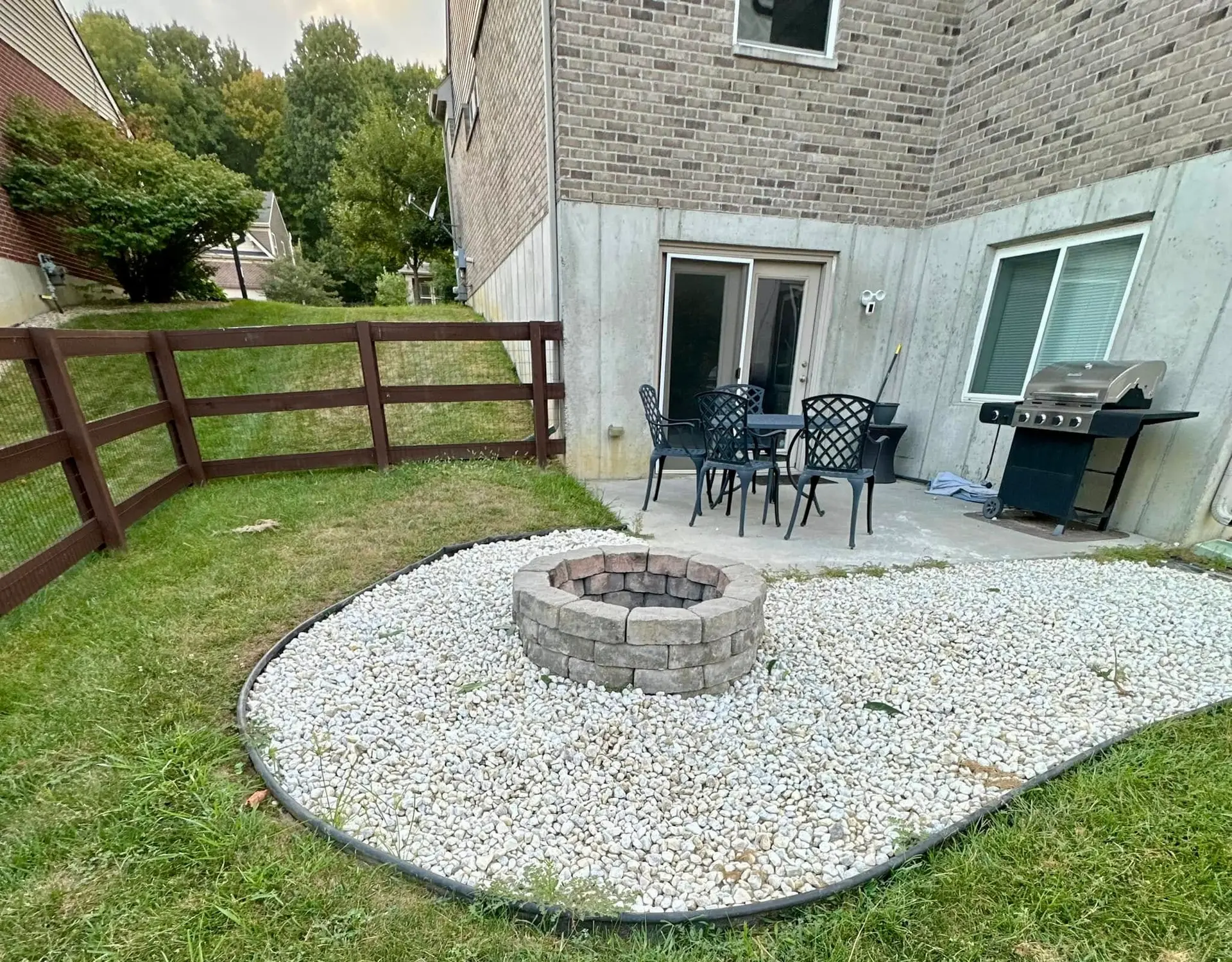 Concrete patio with stone firepit on white rock surround at rear yard of residential home