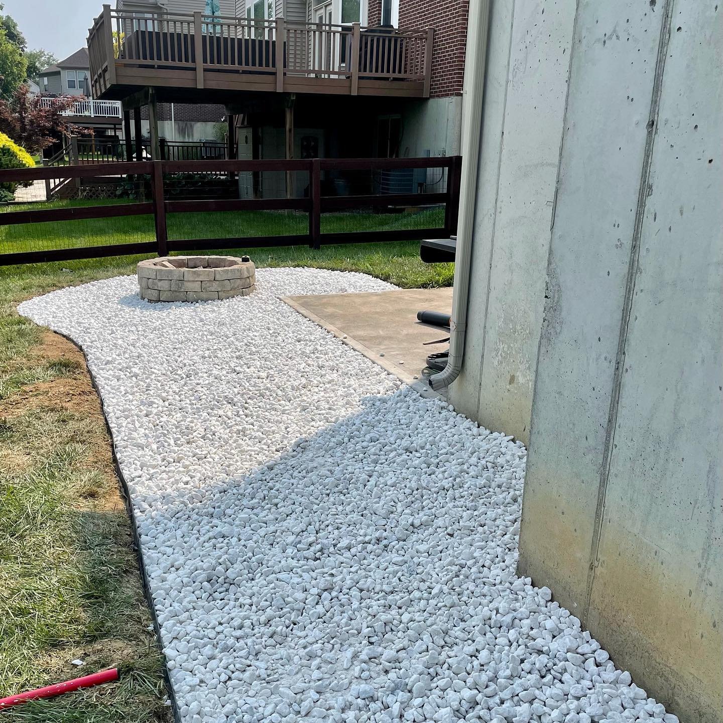 French drain with white rock around a firepit drainage area