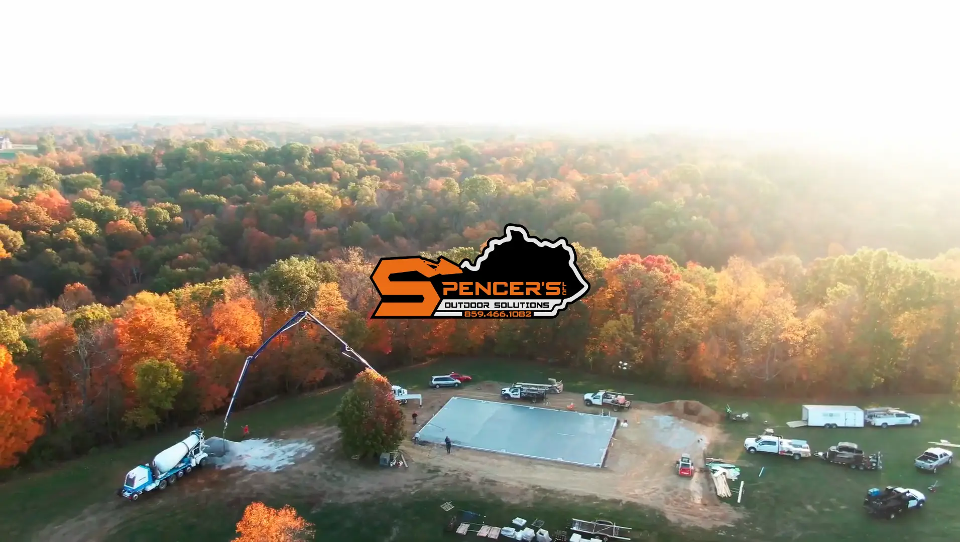 Aerial view of a dense autumn forest with an orange Spencer's Outdoor Solutions logo overlay in the center.